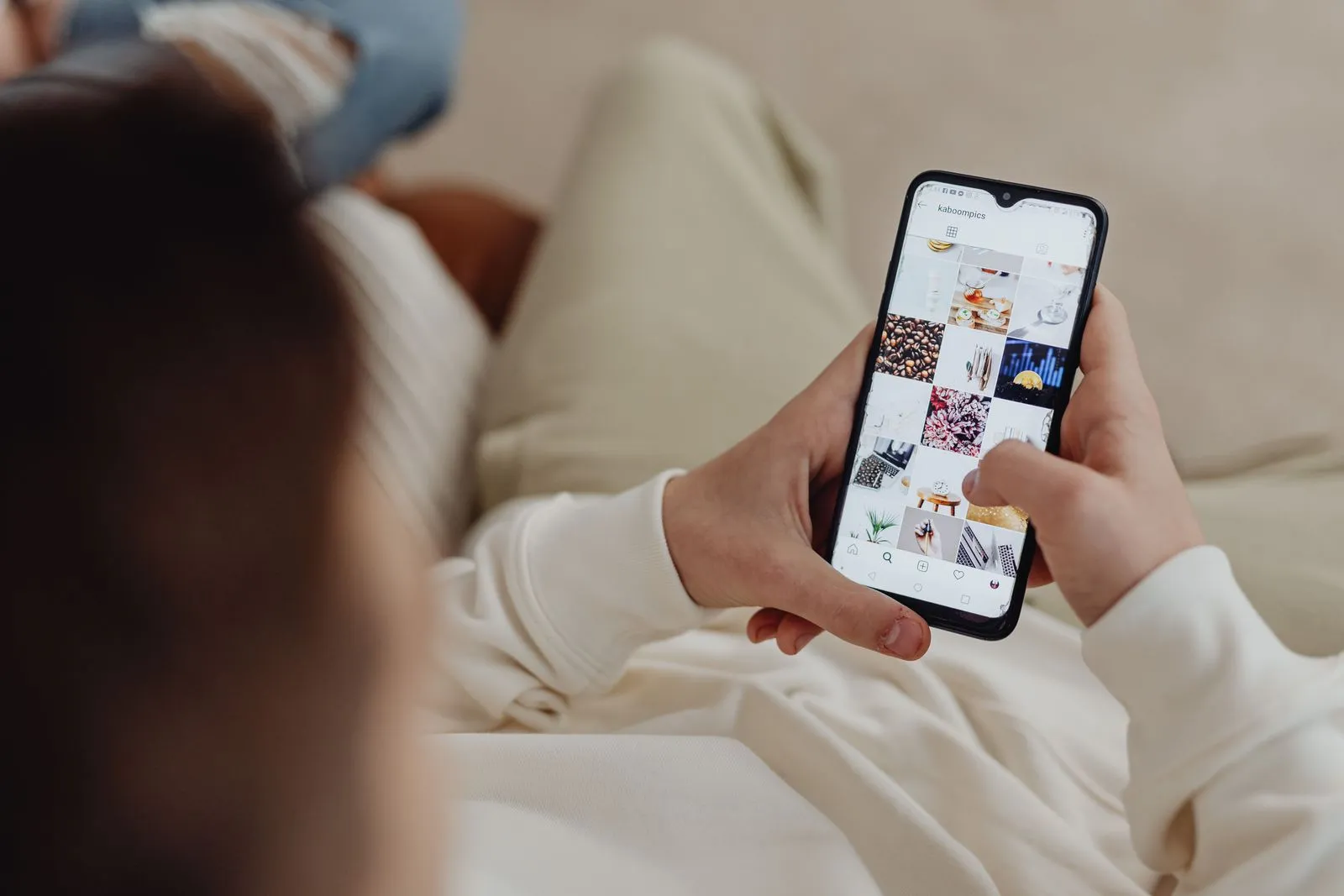 Hand hält ein Smartphone mit einem Instagram-Feed voller Bilder