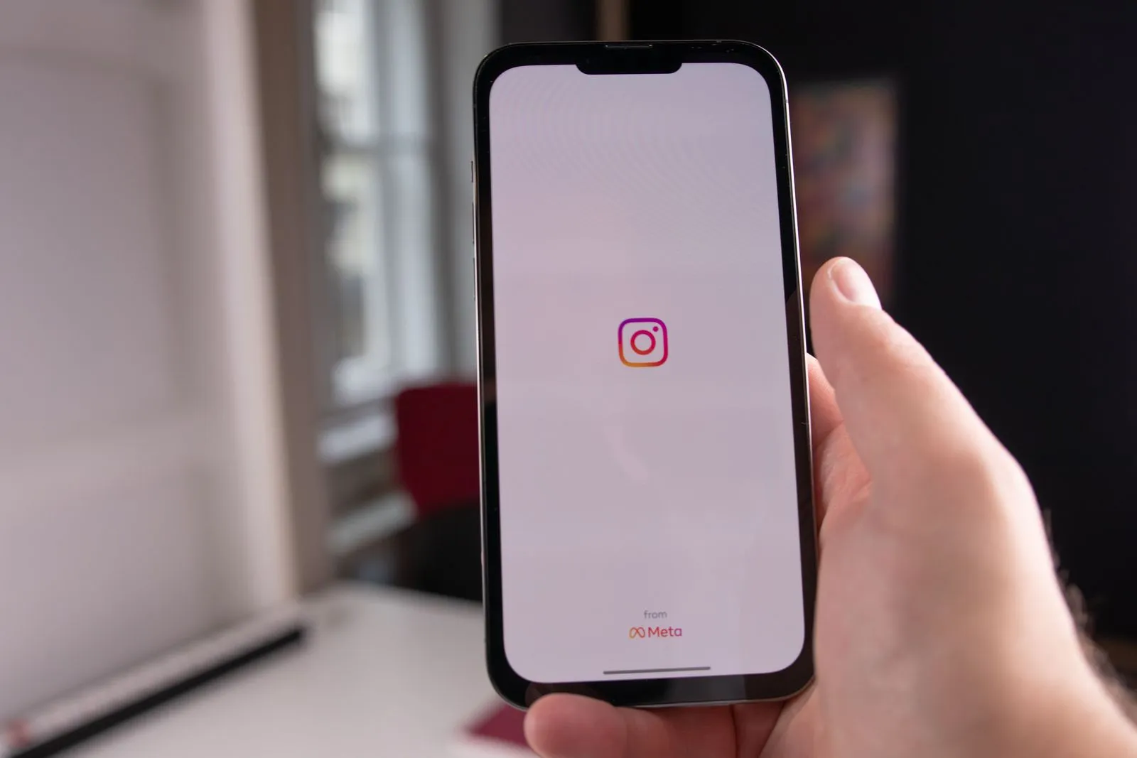 Eine Hand hält ein Smartphone, auf dem der Startbildschirm der Instagram-App zu sehen ist