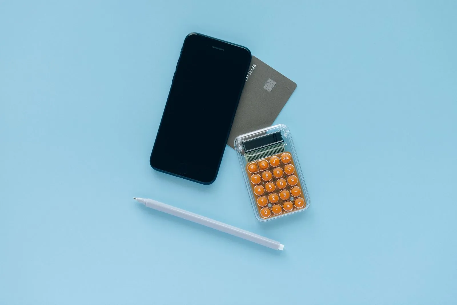 Smartphone, bank card, calculator and pen on a light blue background