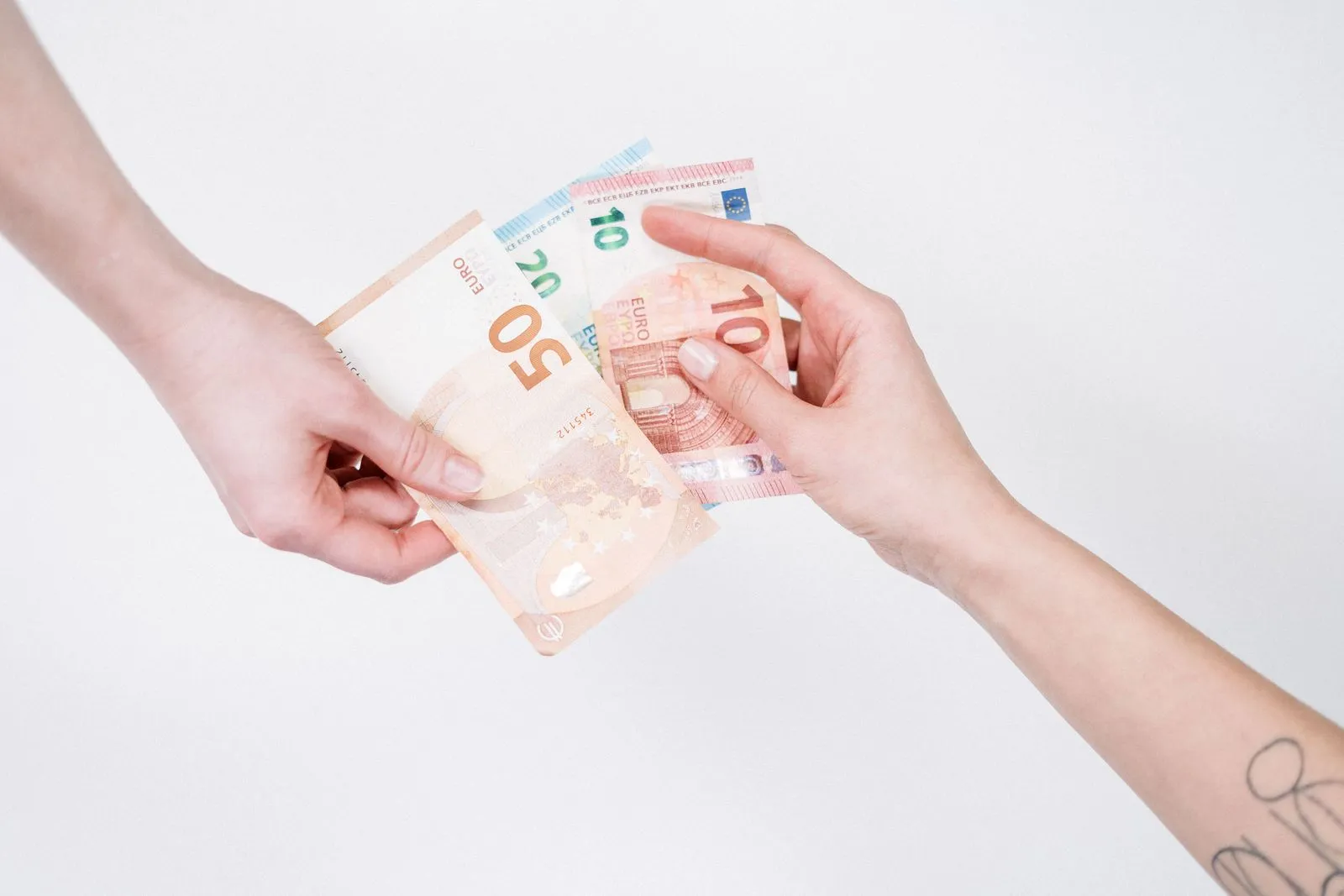 Zwei Hände übergeben Euro-Banknoten vor einem weißen Hintergrund