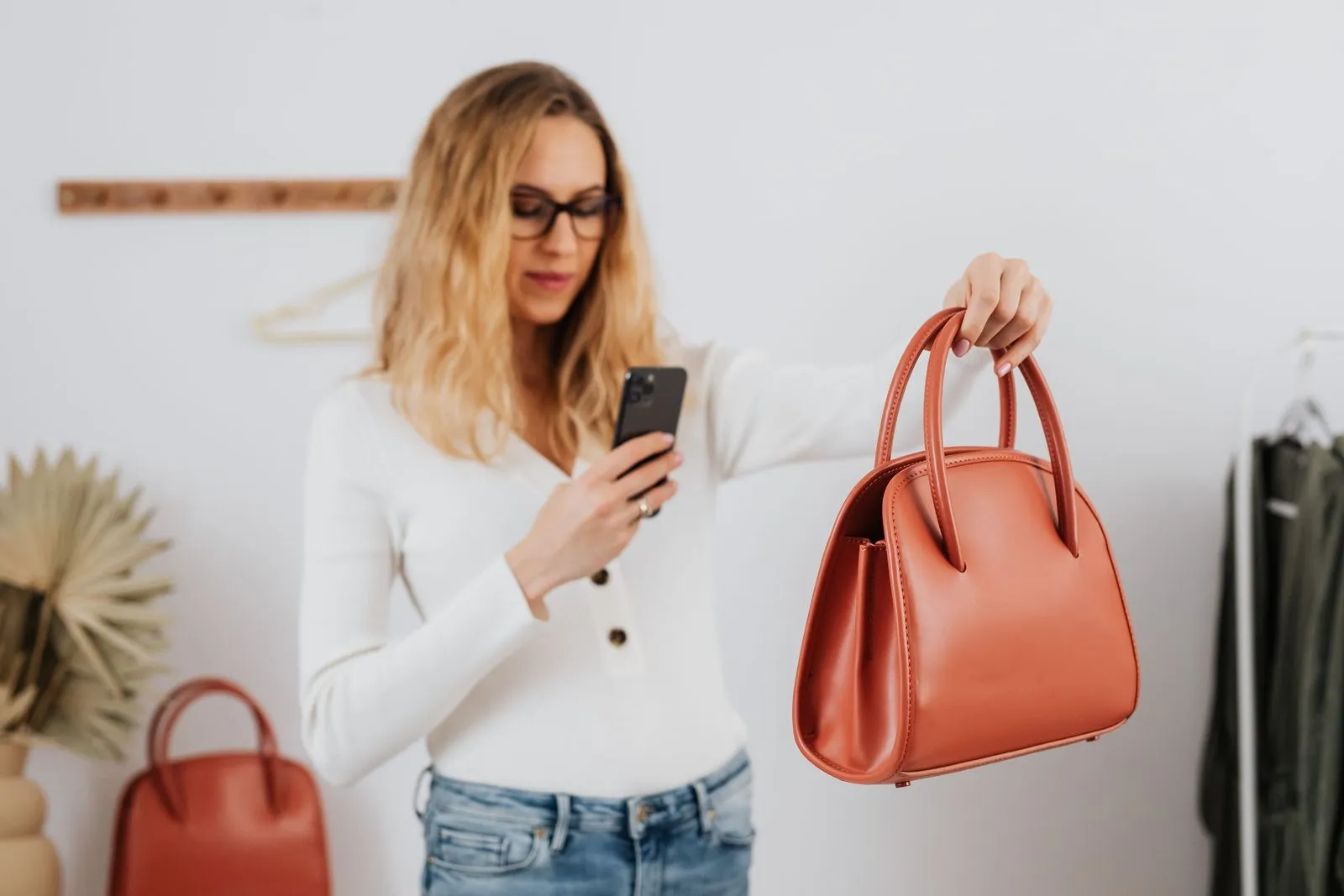 Frau fotografiert eine Handtasche mit dem Smartphone, um sie online zu verkaufen