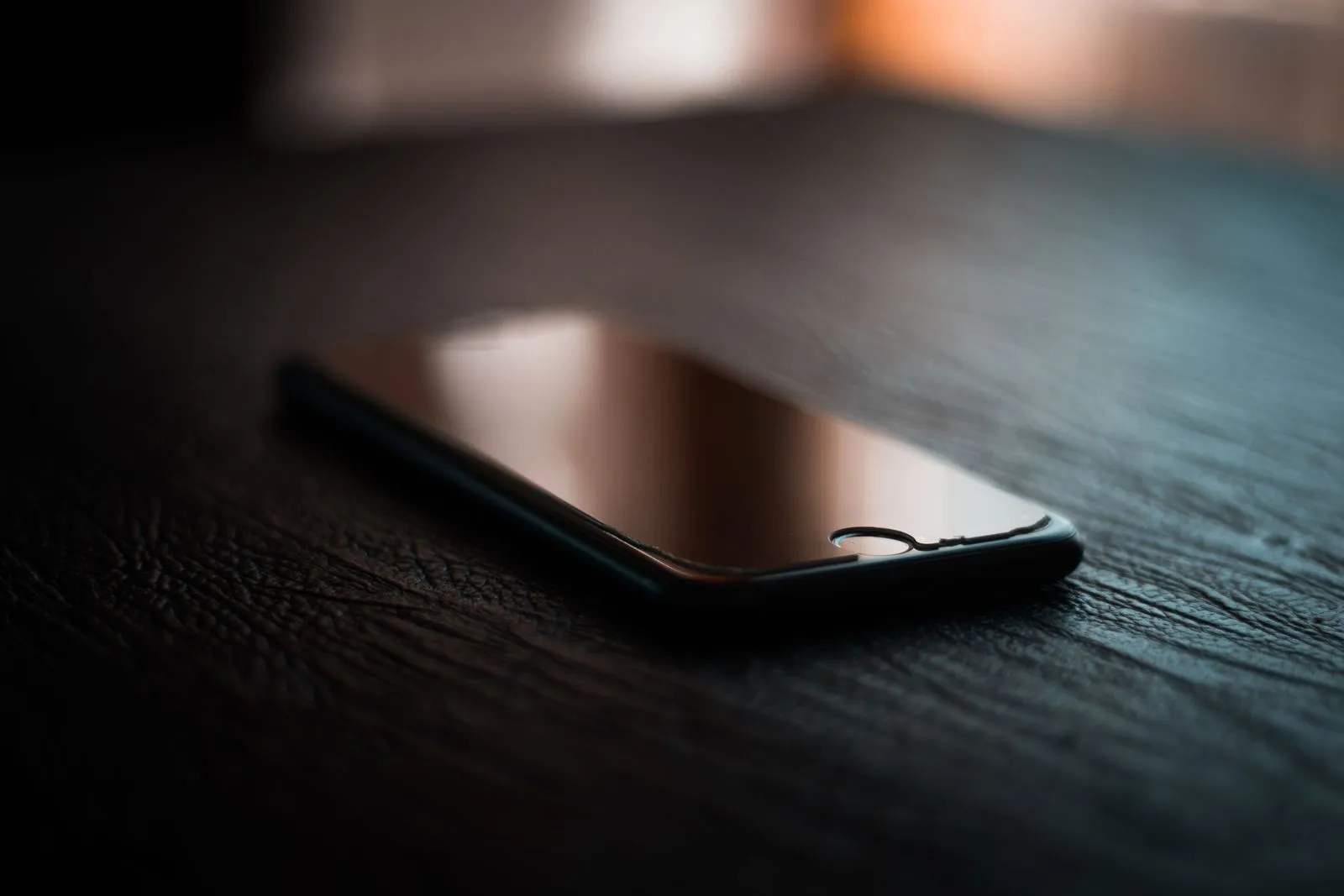 Ausgeschaltetes Smartphone liegt im Halbdunkel auf einem dunklen Tisch