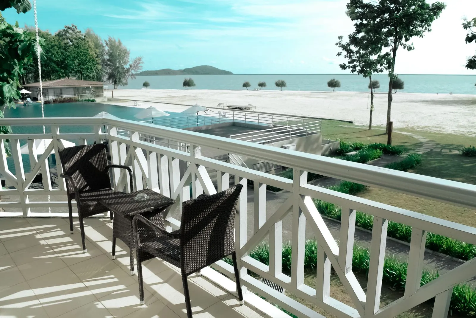 Balkon mit zwei Korbstühlen und Blick auf Pool, Strand und Meer